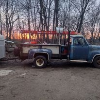 A blue truck with a trailer attached to it is parked in a parking lot.
