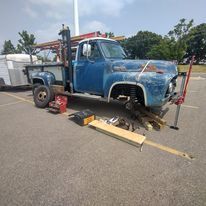 A blue truck with a forklift attached to it is parked in a parking lot.