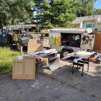 A truck is parked in a driveway next to a table saw.