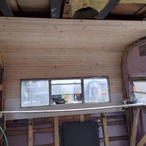 A room with a wooden ceiling and a lot of windows.