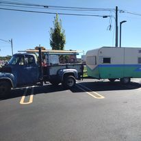 A truck is towing a trailer down a street.