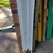 A white garage door is sitting next to a brick wall.