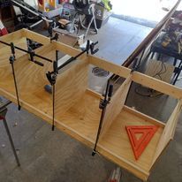 A wooden table with a triangle and clamps on it.