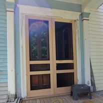 A pair of screened in doors on a porch of a house.