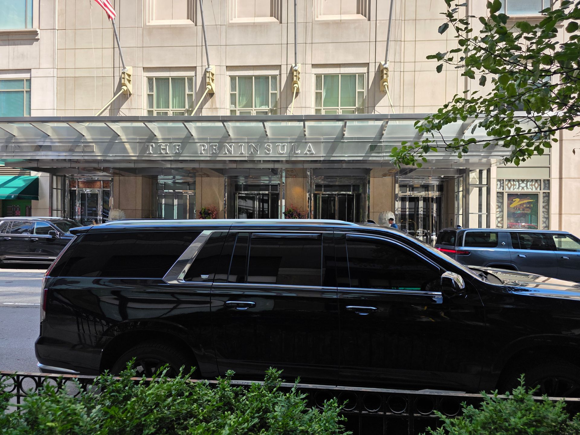 Black SUV in front of a light-colored building with a glass entrance; sunny day.