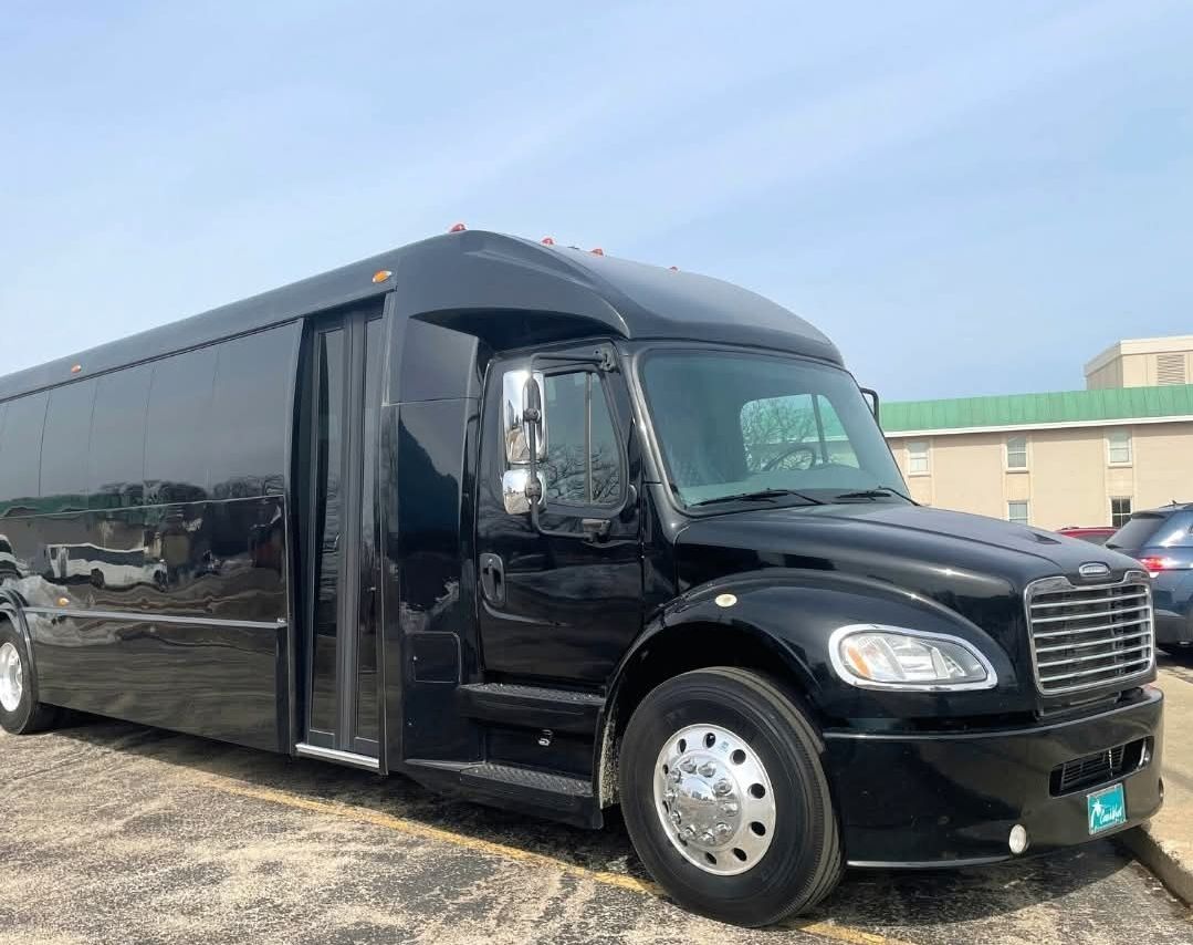 Black party bus parked in a parking lot on a sunny day.