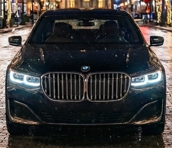 A bride and groom are standing next to a white limousine.