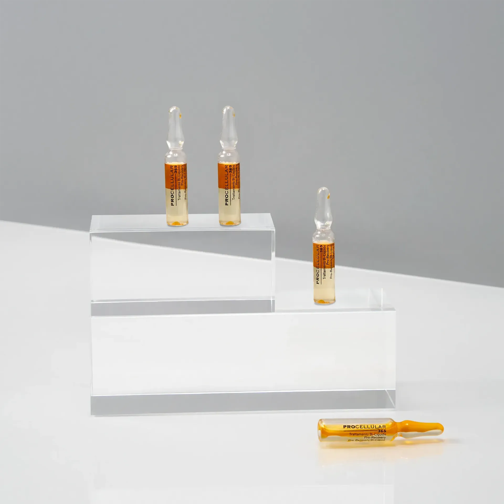 Quattro fiale color ambra su blocchi trasparenti, una fiala è distesa.