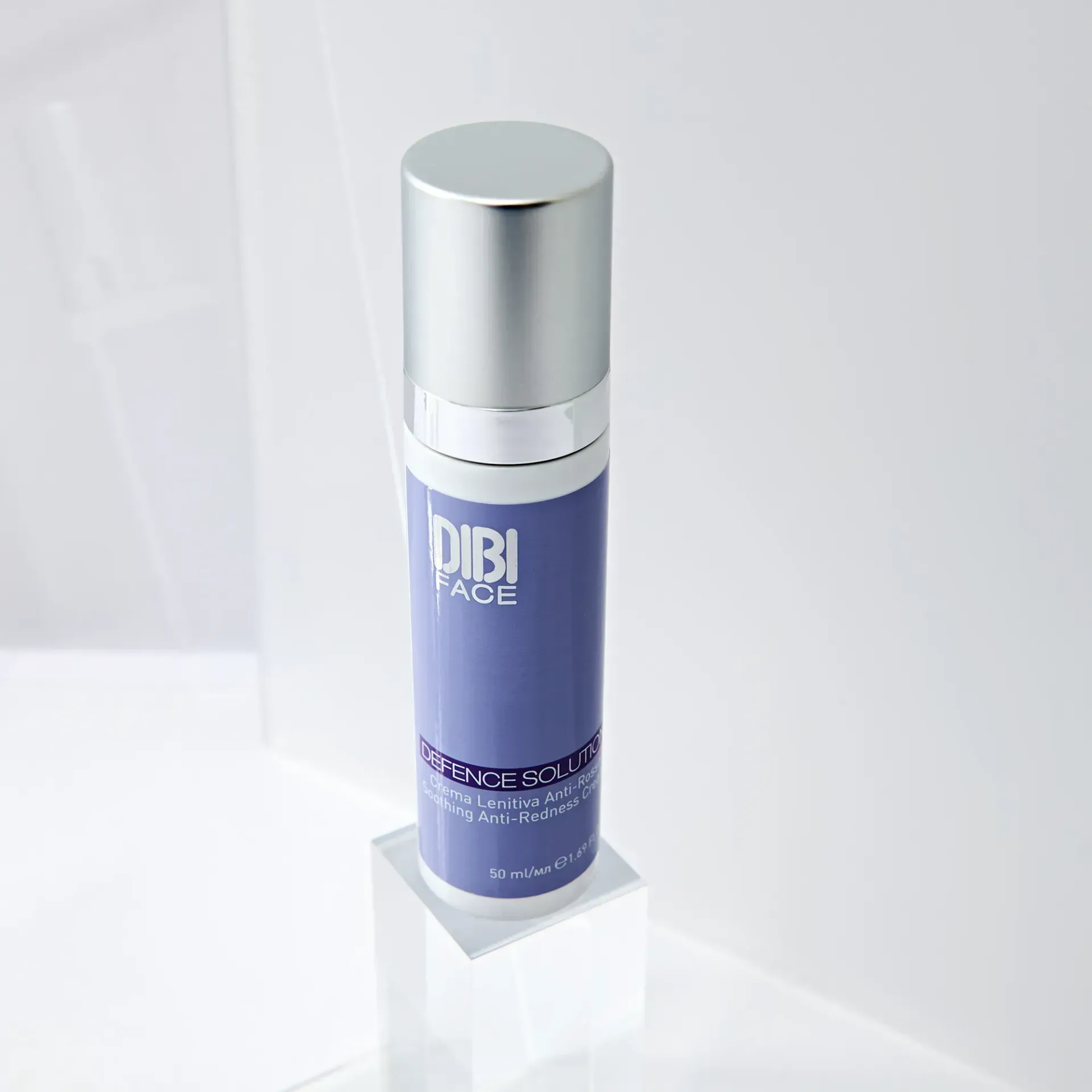 Un flacone di prodotto per la cura della pelle DIBI Face viola e argento su un piedistallo bianco.