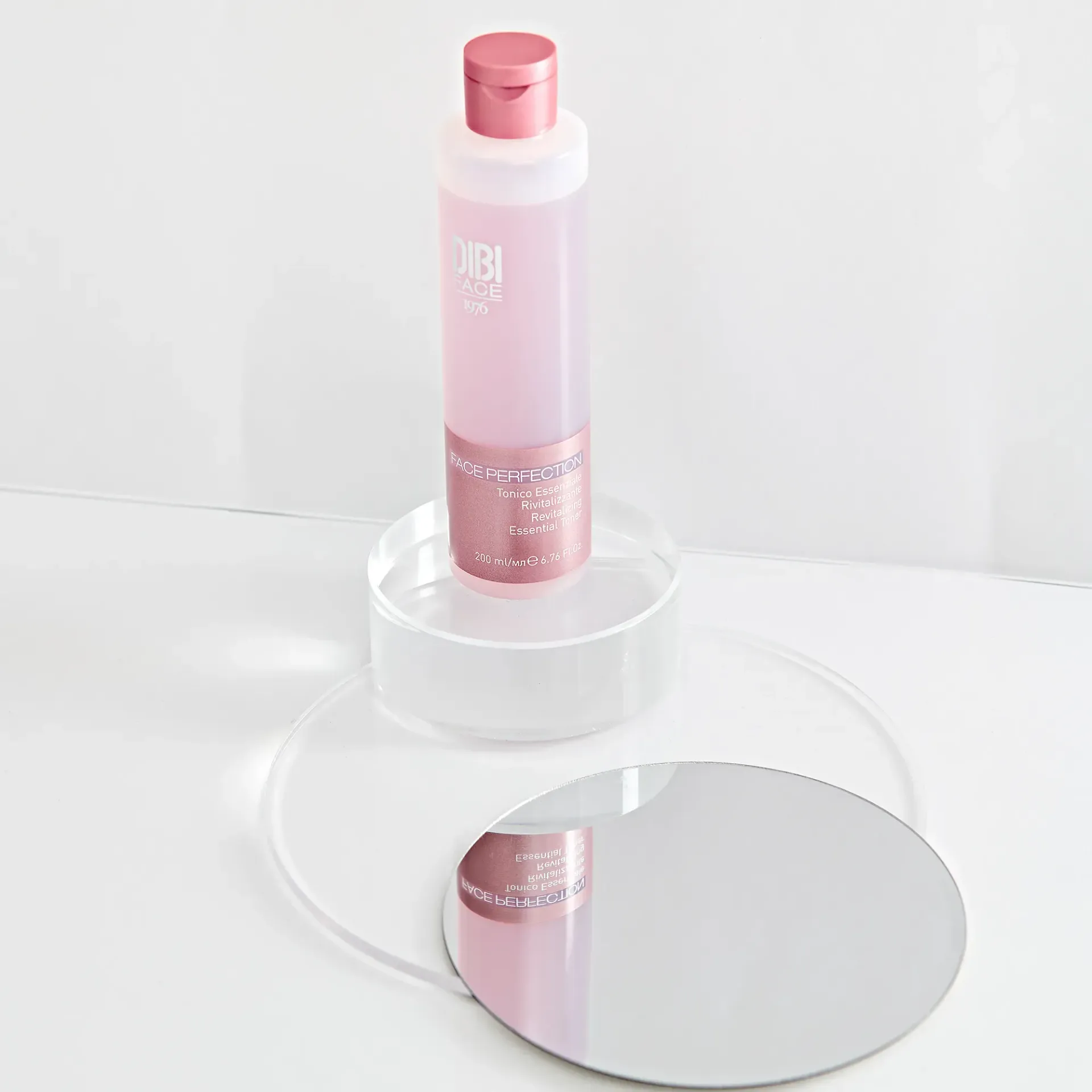 Flacone rosa di prodotto per la cura della pelle su un espositore circolare trasparente con base a specchio.