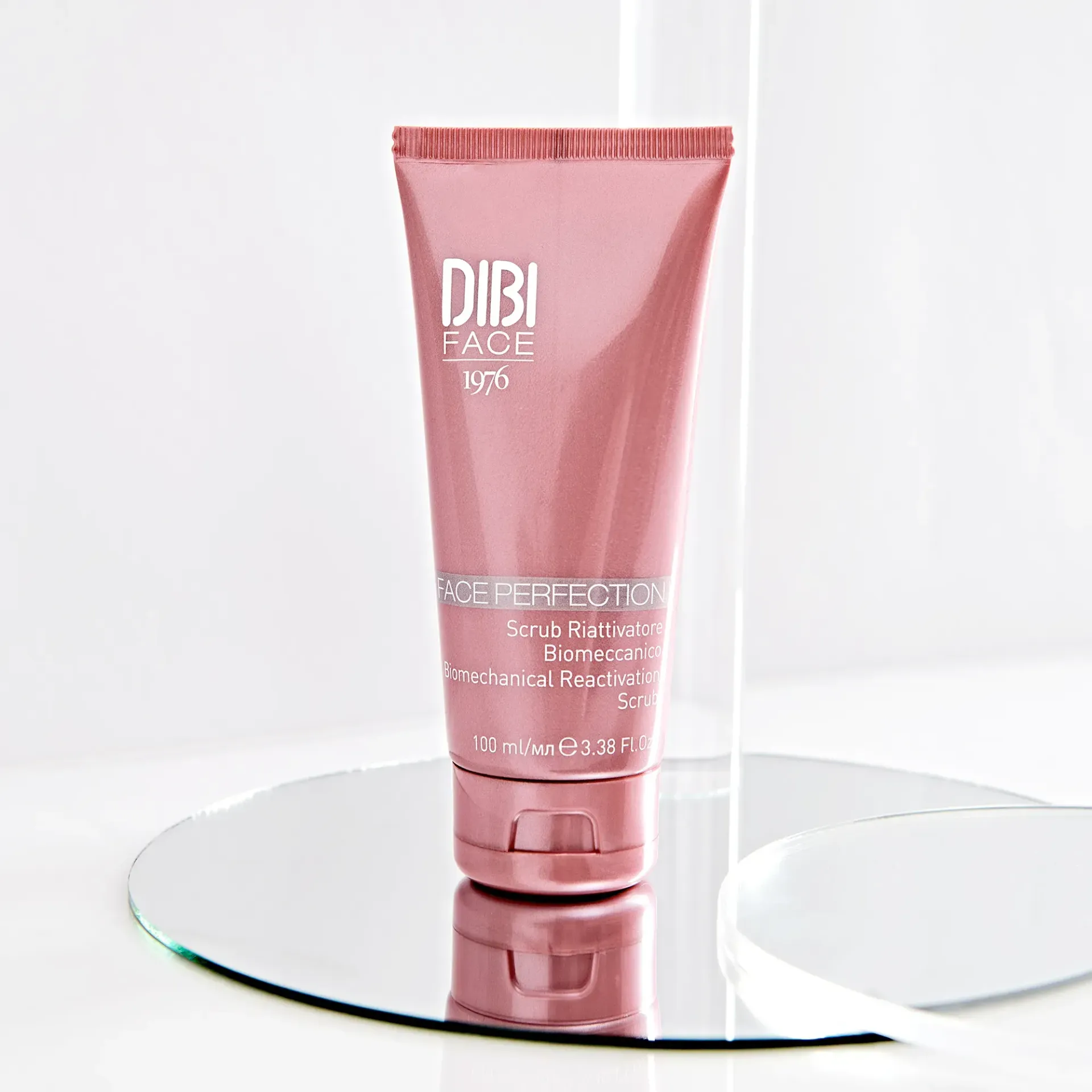 Tubetto rosa di scrub per la pelle DIBI FACE su superficie riflettente.