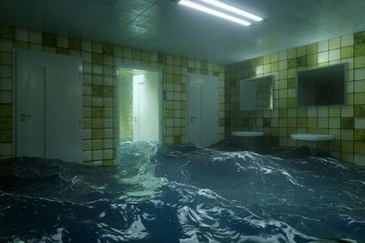 Flooded tiled room with open doors, bright ceiling lights, and choppy water covering the floor.