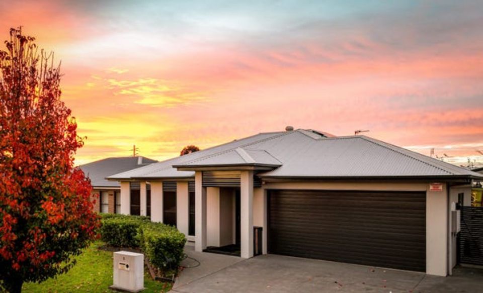 A house with a garage and a sunset in the background.