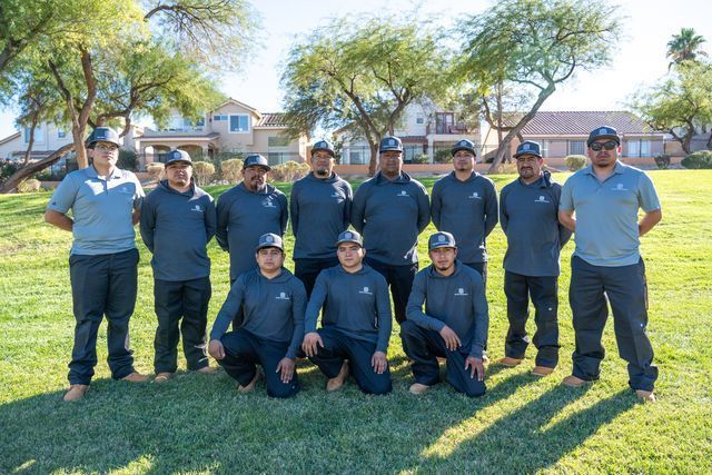 Group of people in uniform posing on a grassy field in front of a house.