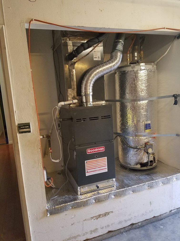 Furnace and water heater in a utility closet with vent pipes. Gray and silver with some wiring.