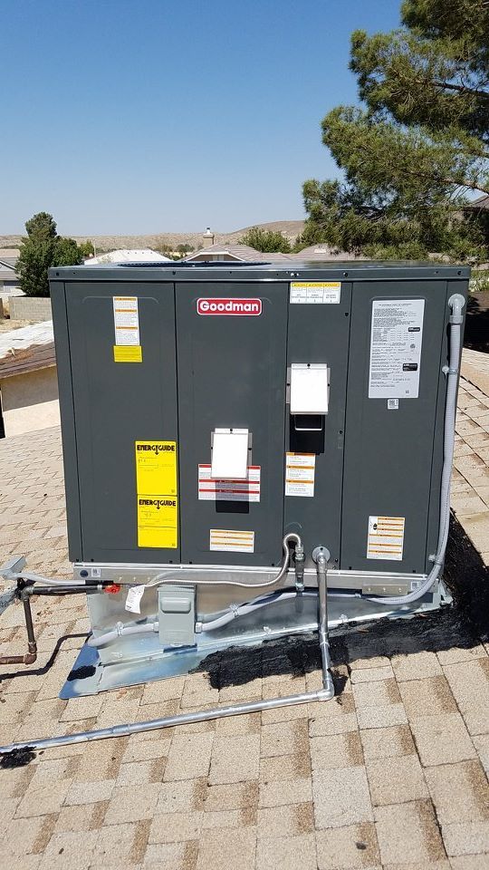 A rooftop air conditioning unit on a residential roof, gray metal box, with safety bars.