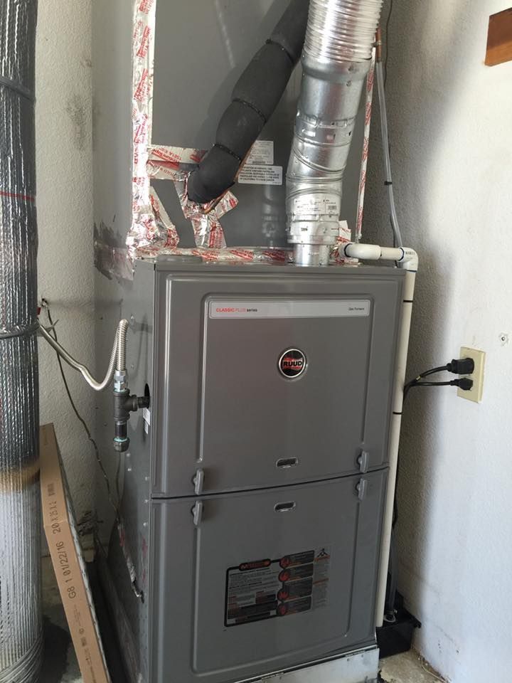 Gray furnace with ductwork in a utility room.