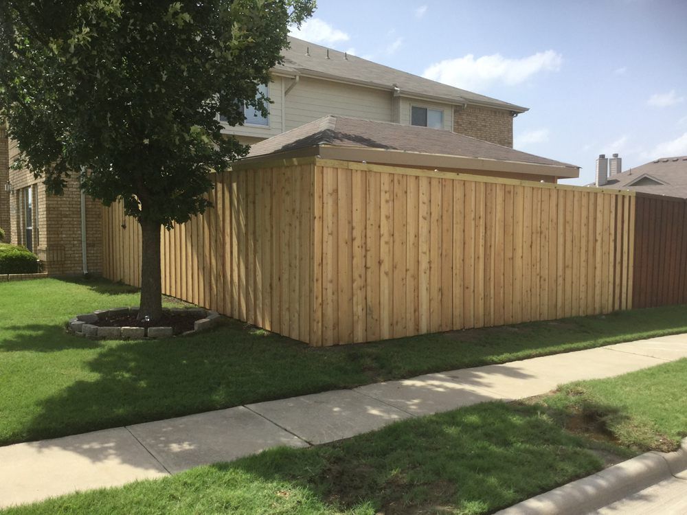 A wooden fence is in front of a house.