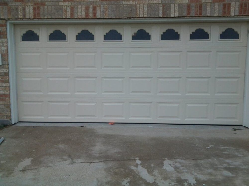 A white garage door is sitting in front of a brick building.