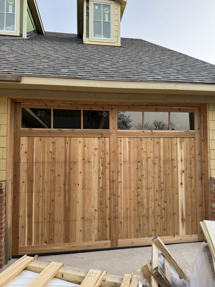 A wooden garage door is being installed on a house