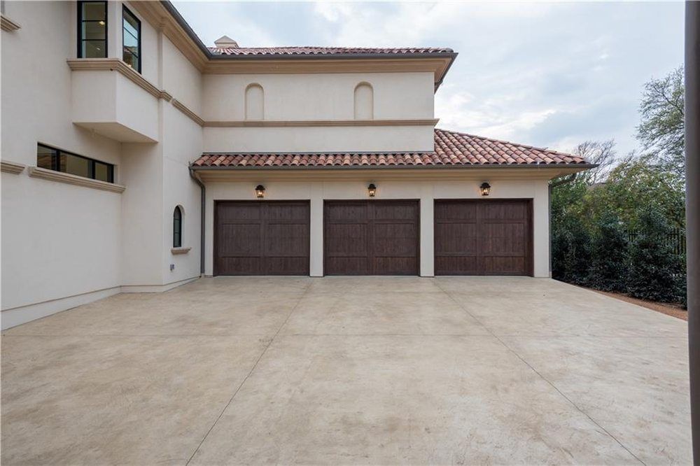 A large white house with three brown garage doors