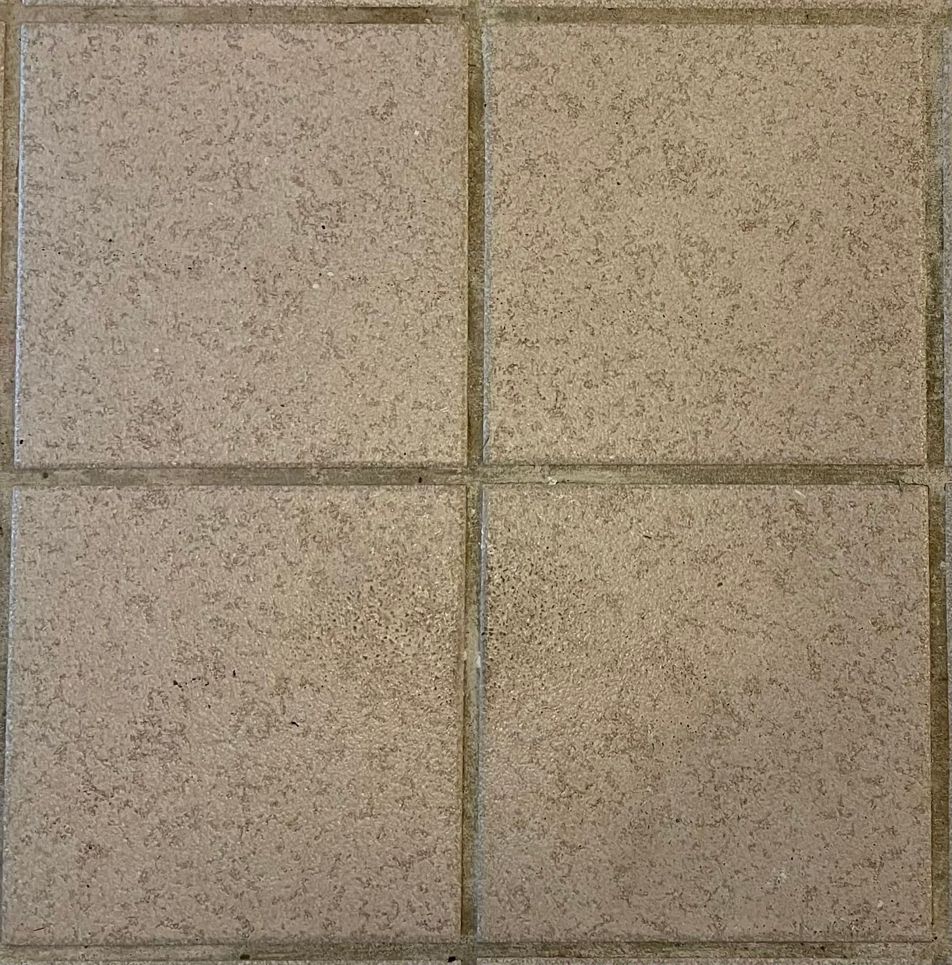 Four square tan concrete pavers arranged in a 2x2 grid with dark seams