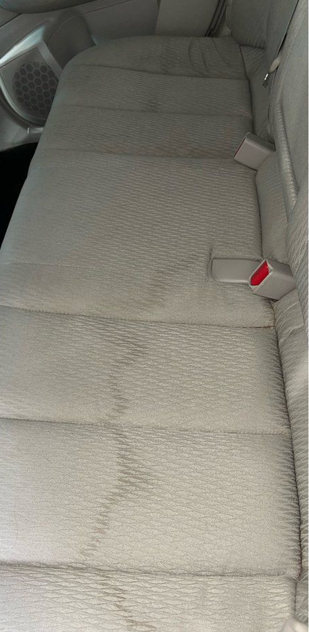 Gray quilted car back seat with a red seat belt buckle visible