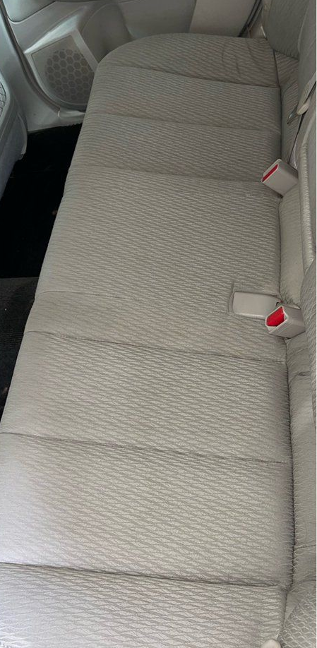 Light gray patterned car rear seat with two red seat belt buckles