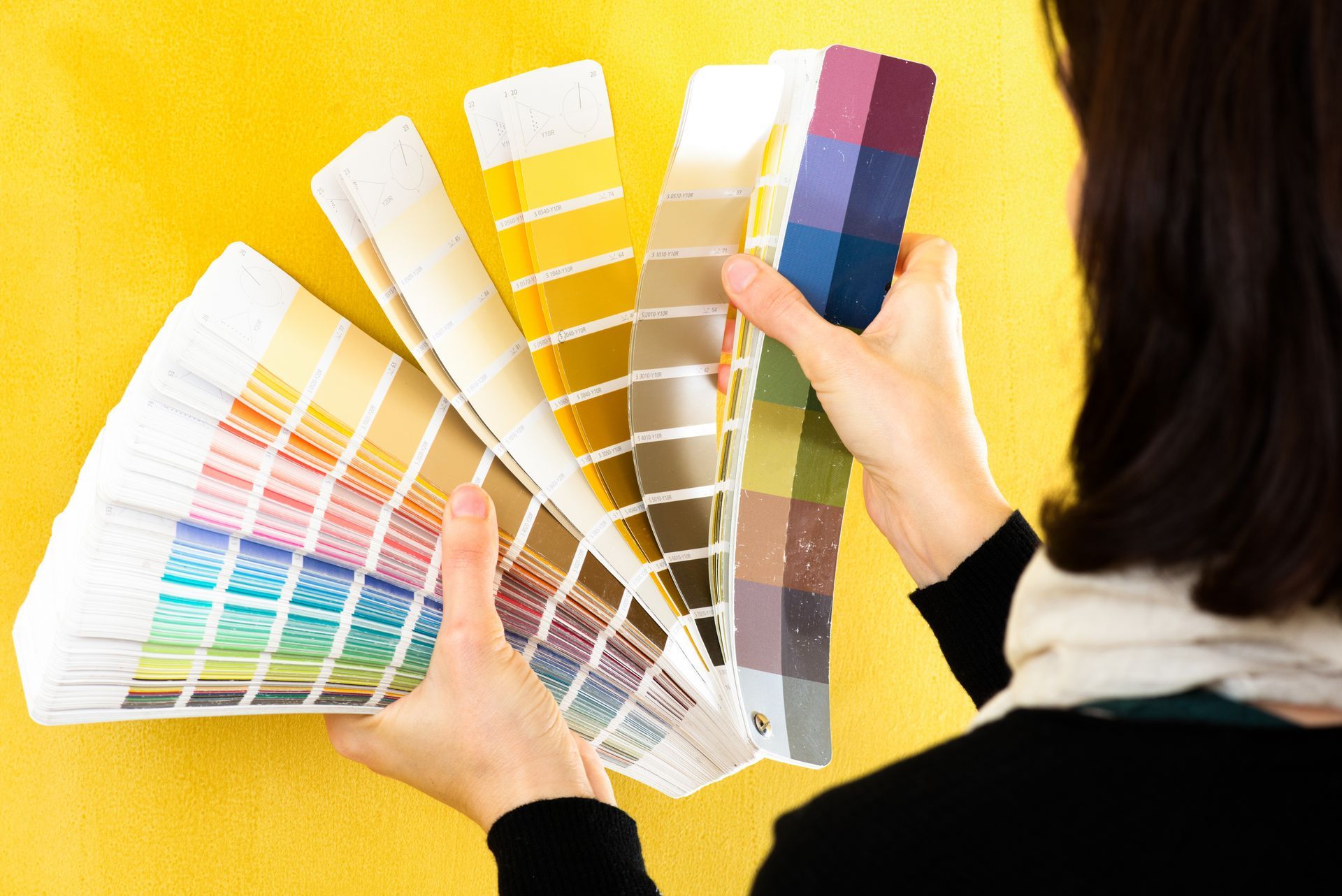 A woman is holding a fan of color samples in her hands.