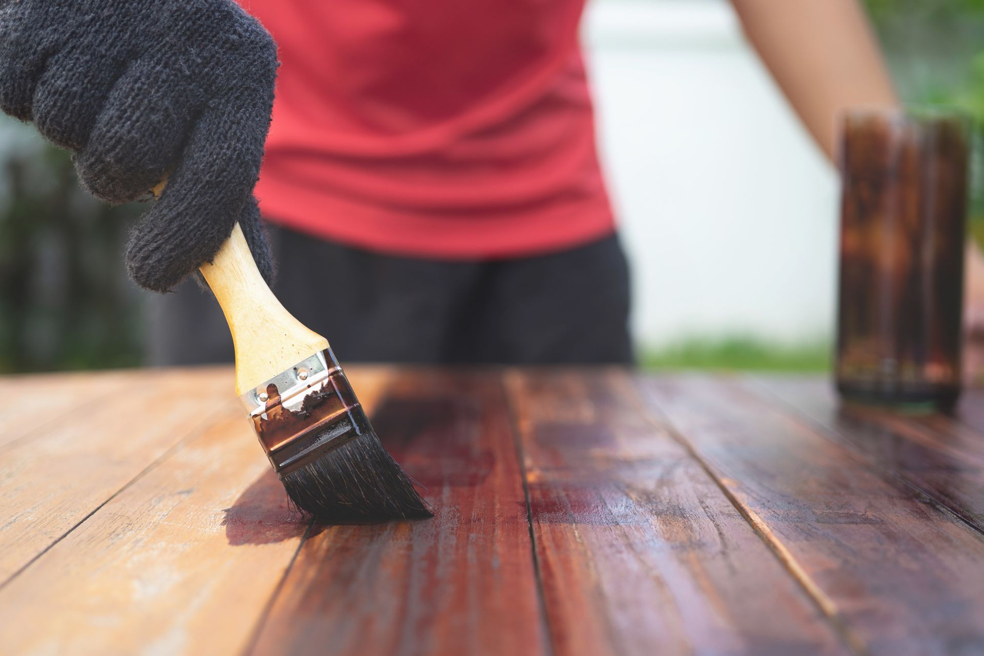 A person is painting a wooden table with a brush.