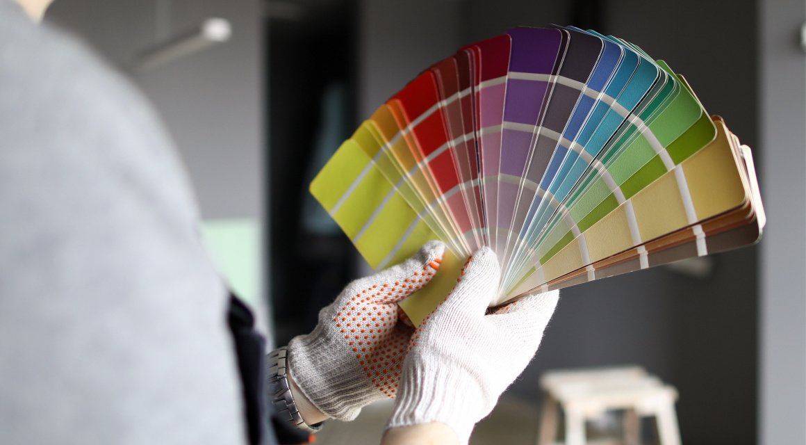 A person is holding a fan of paint samples in their hands.