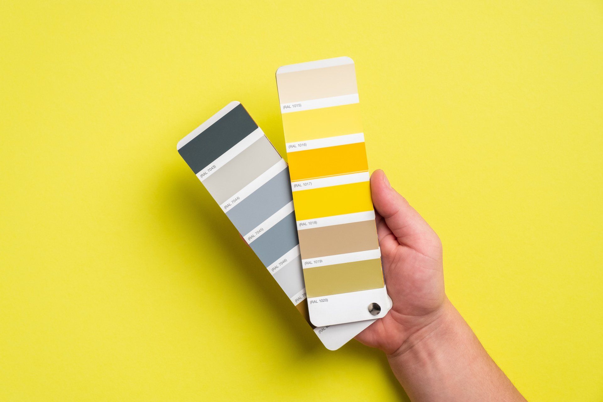 A person is holding a color palette on a yellow background.