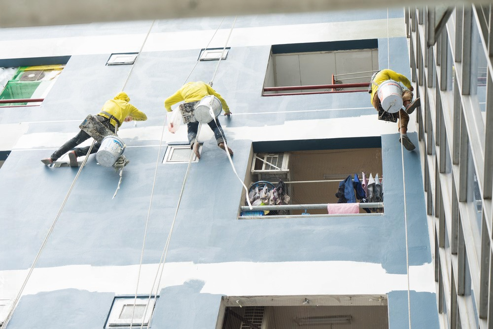 A group of people are painting the side of a building.