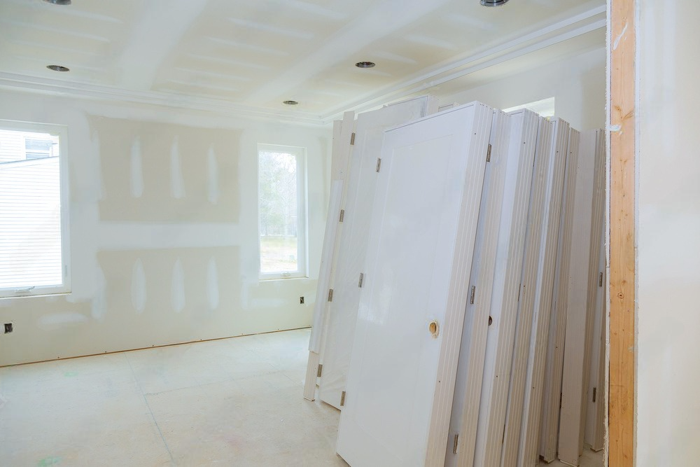 A room under construction with a stack of drywall boards.