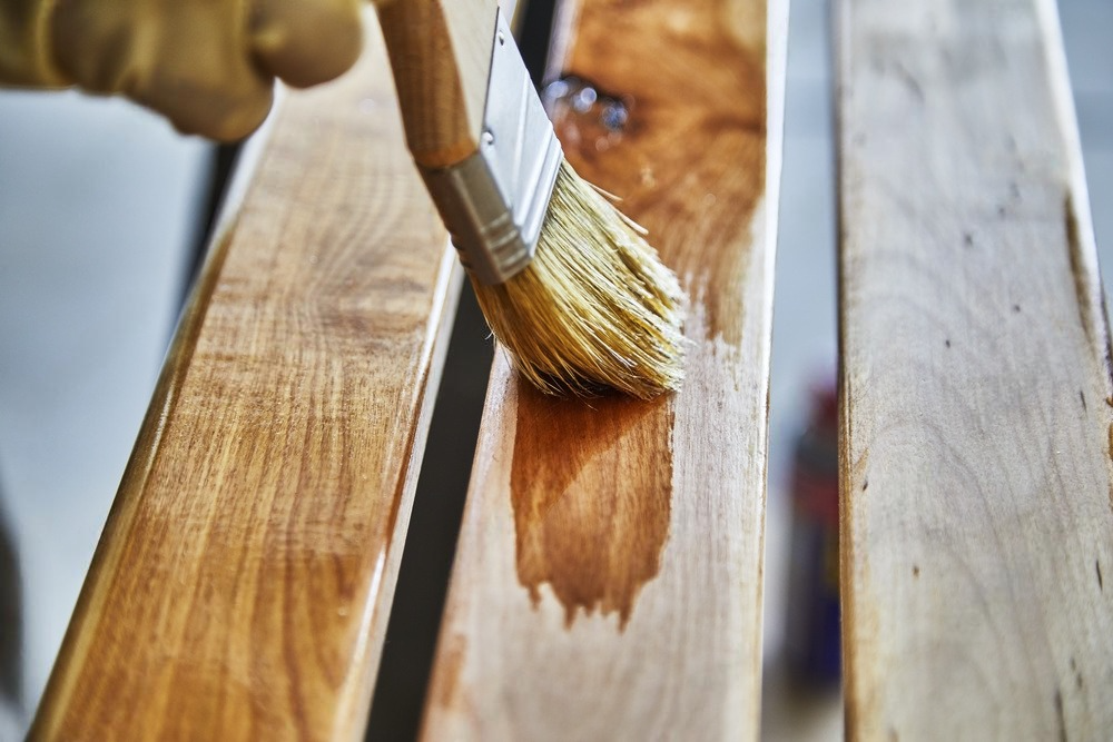 A person is painting a piece of wood with a brush.