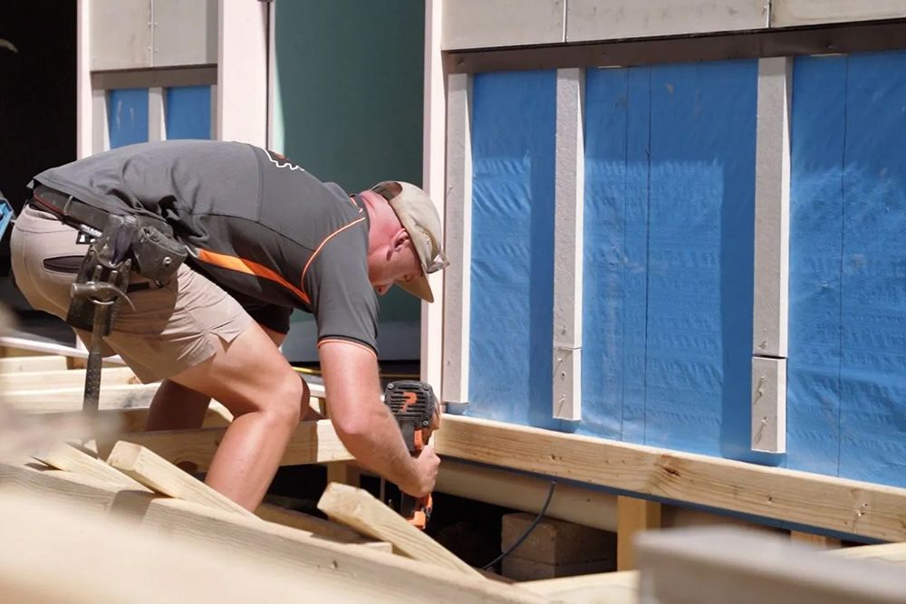 A Man Is Working On A Wooden Structure With A Drill — Entire Trades in Port Stephens, NSW