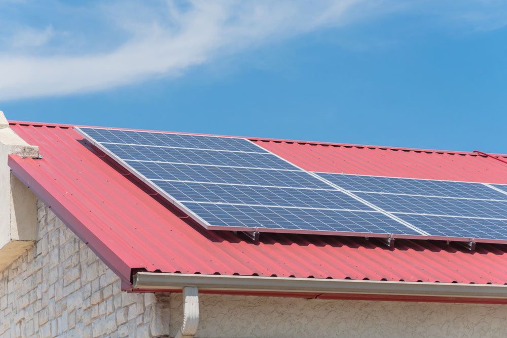 A Red Roof With Solar Panels On Installed On It — Entire Trades in Maitland, NSW