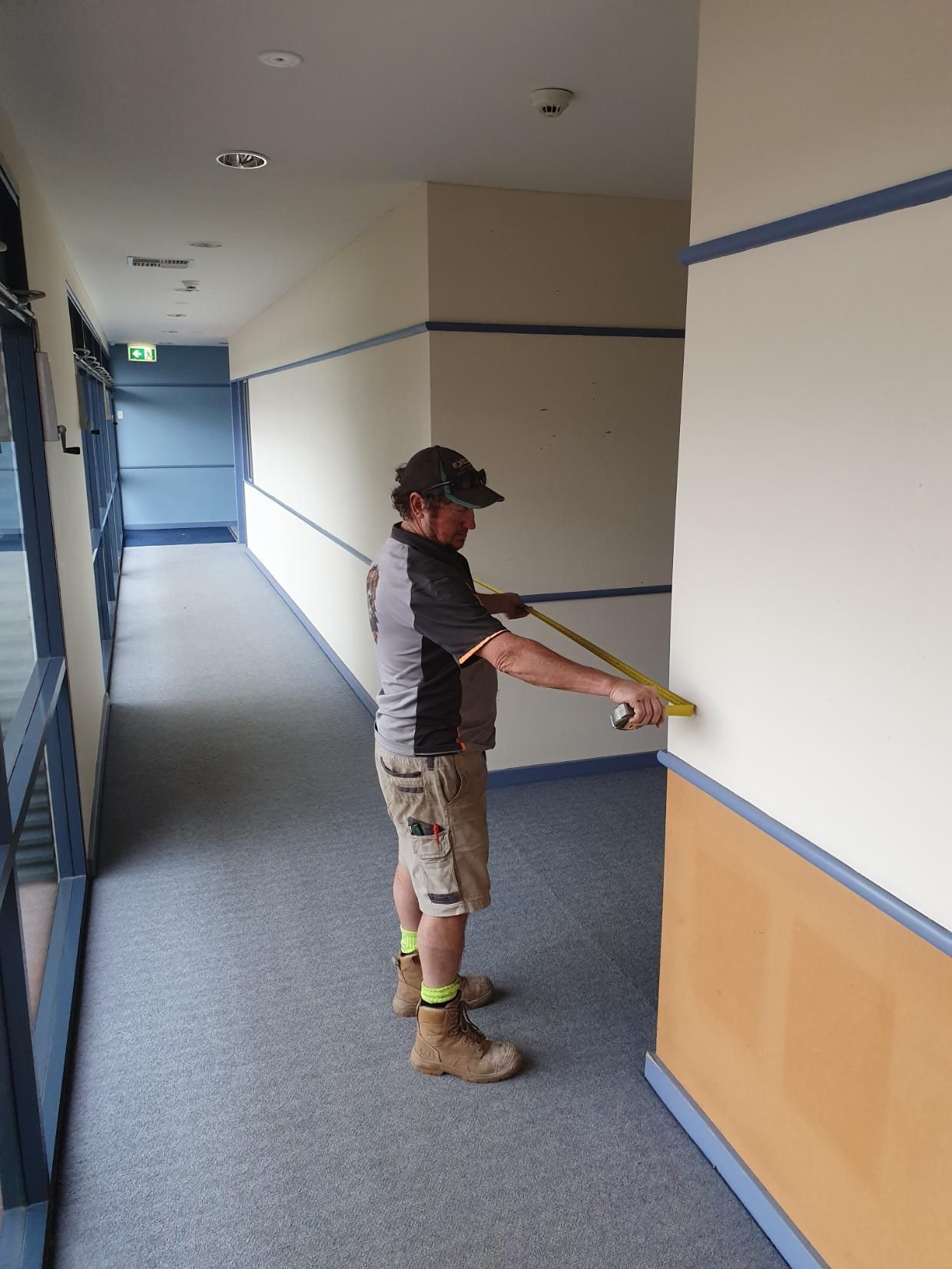 A Man Is Measuring a Wall with A Tape Measure — Entire Trades in Maitland, NSW