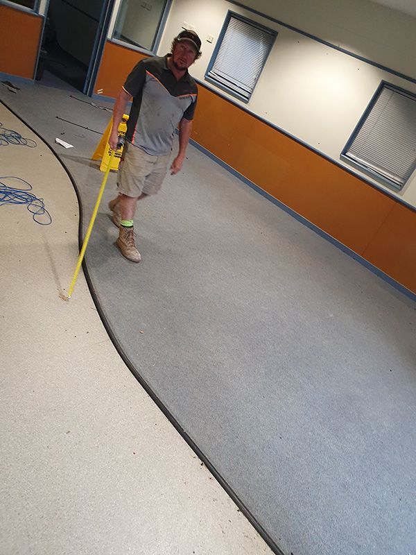 A Man Is Measuring A Carpet With A Tape Measure — Entire Trades in Cessnock, NSW