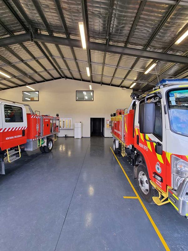 Two Fire Trucks Are Parked Inside A Spacious Warehouse With Light Open — Entire Trades in Cessnock, NSW