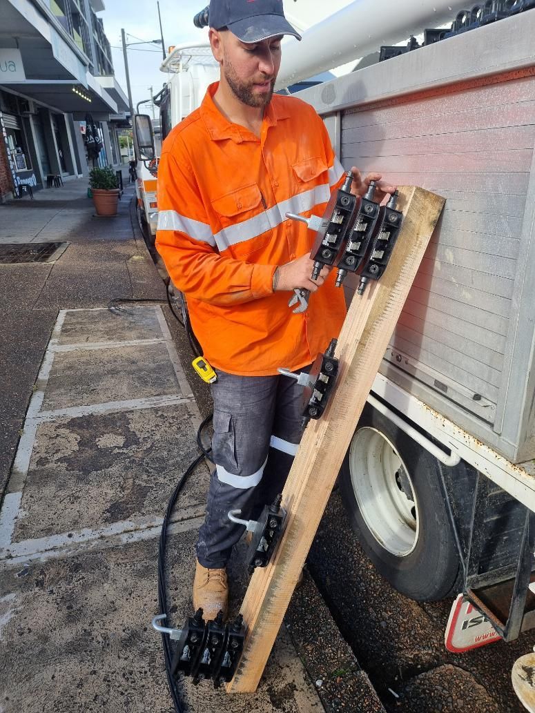 A Man in An Orange Shirt Is Standing Next to A Truck — Entire Trades in Maitland, NSW