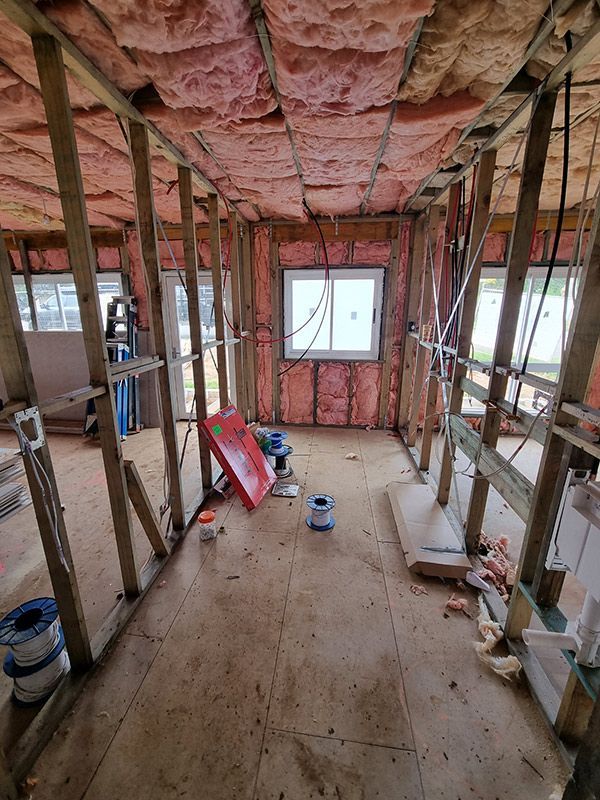 Interior View Of A Bathroom Showcasing Pink Insulation And A Standard White Toilet In The Corner — Entire Trades in Port Stephens, NSW
