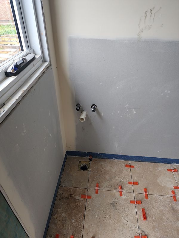 A Bathroom Under Construction With Tiles On The Floor And A Window — Entire Trades in Central Coast, NSW