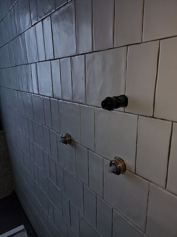 A Bathroom Wall With White Tiles And Two Faucets — Entire Trades in Central Coast, NSW
