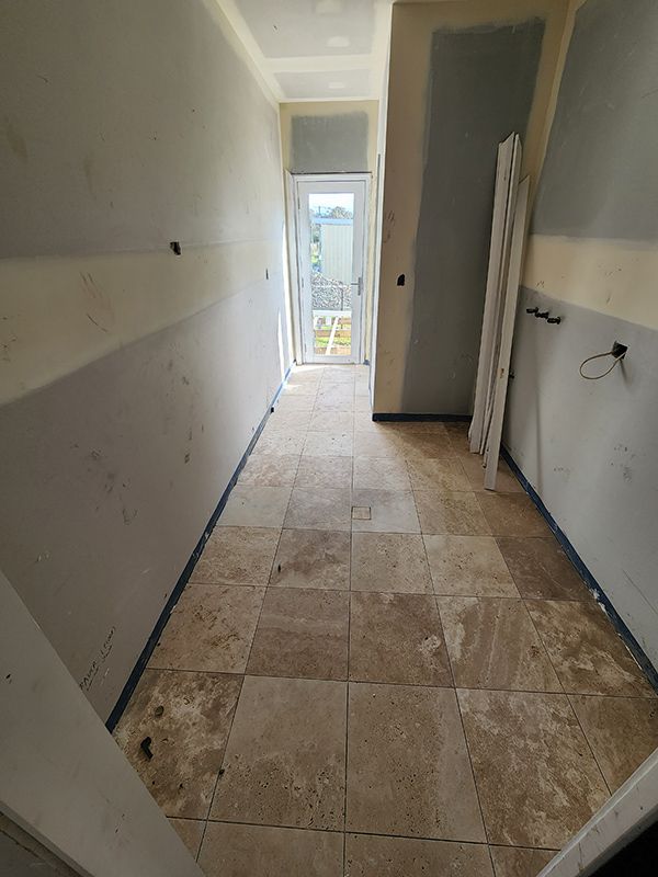 A Long Hallway With Tile Floors And A Door Under Construction — Entire Trades in Cessnock, NSW