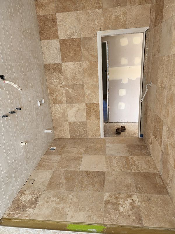 A Bathroom Renovation With A Tiled Floor And A Door — Entire Trades in Central Coast, NSW