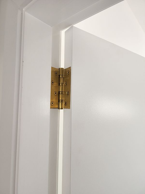 A Close Up Of A Brass Door Hinge On A White Door — Entire Trades in Singleton, NSW
