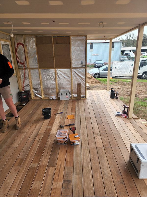 A Man Is Standing In A Room With A Wooden Floor — Entire Trades in Central Coast, NSW