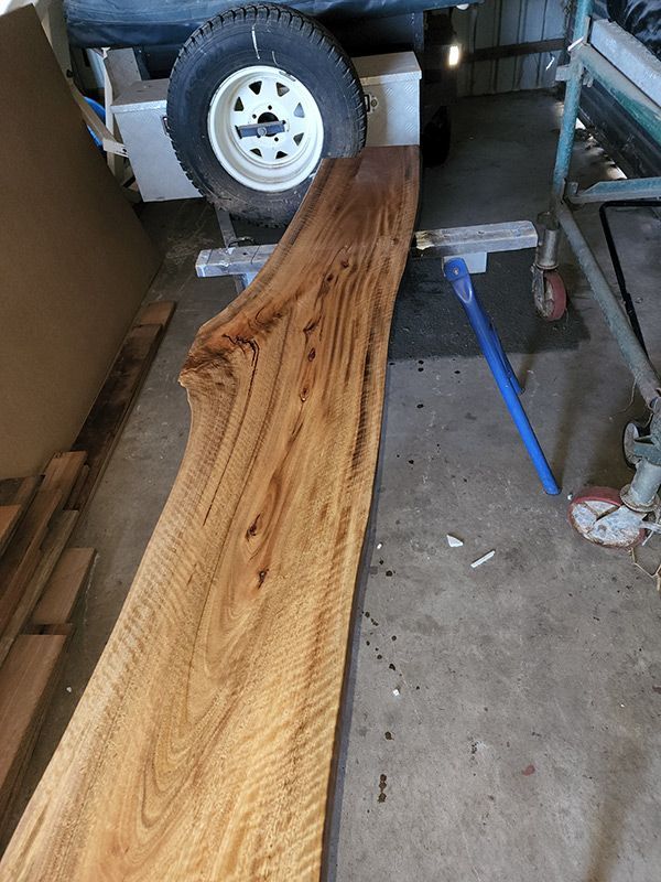 A Large Piece Of Wood Is Sitting In A Garage Next To A Trailer — Entire Trades in Singleton, NSW
