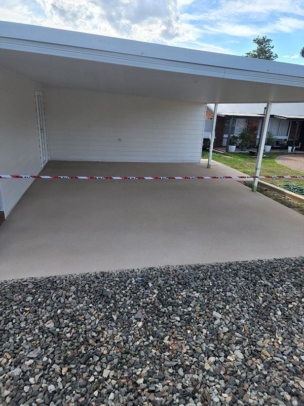 A Concrete Driveway With Gravel Leading To A White Garage — Entire Trades in Port Stephens, NSW